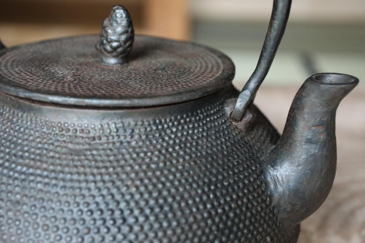 A close-up image of a black metal teapot with a textured surface and a small finial on top.