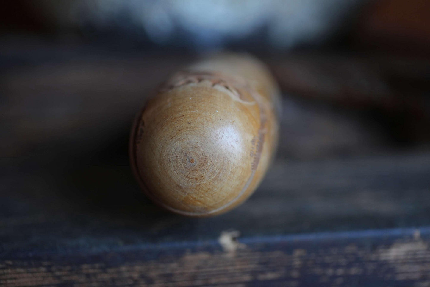 A close-up view of a wooden object, possibly a piece of furniture or a tool, with a textured surface and a circular pattern on it.