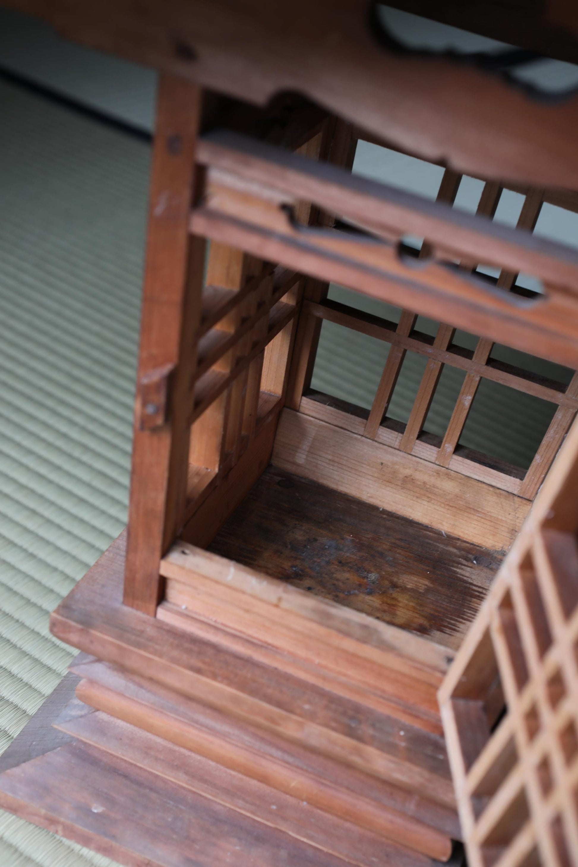 a wooden structure with a lattice-like design, featuring a wooden frame and a wooden panel. The structure appears to be made of wood and has a rustic, weathered look.