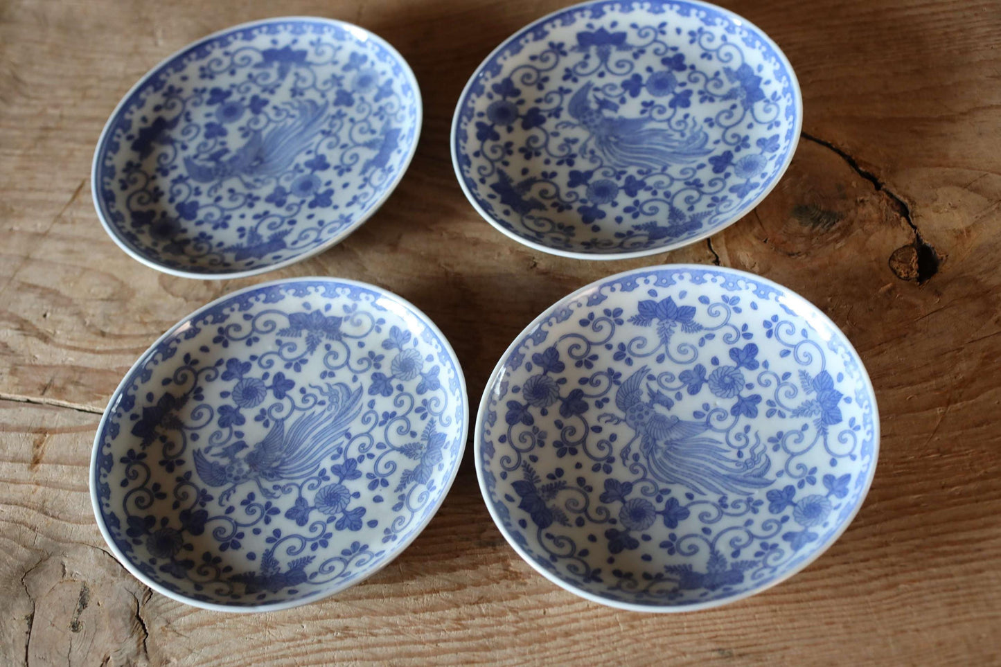 a collection of four blue and white patterned plates arranged on a wooden surface.