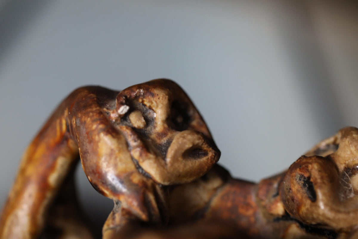 A close-up view of a brown, weathered sculpture with a twisted, gnarled shape.