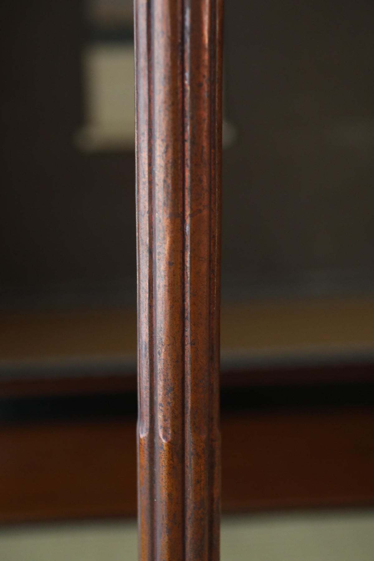 a close-up view of a wooden pole or column, with a blurred background that appears to be a wooden surface or table.