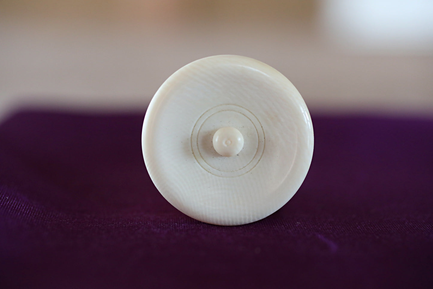 A white, round object with a small circular hole in the center is placed on a purple surface.