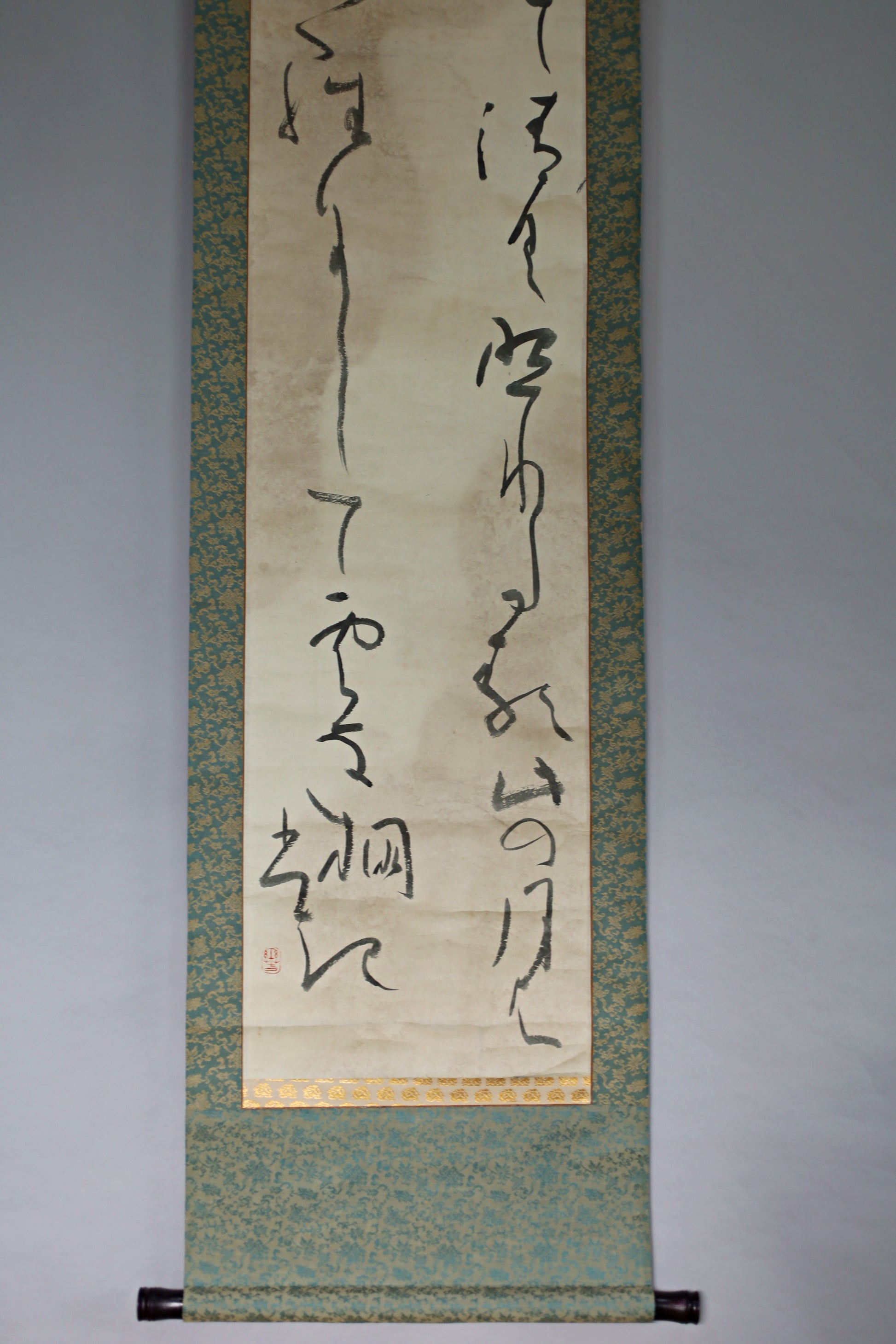 a vertical scroll with Chinese characters on it, hanging on a wall.