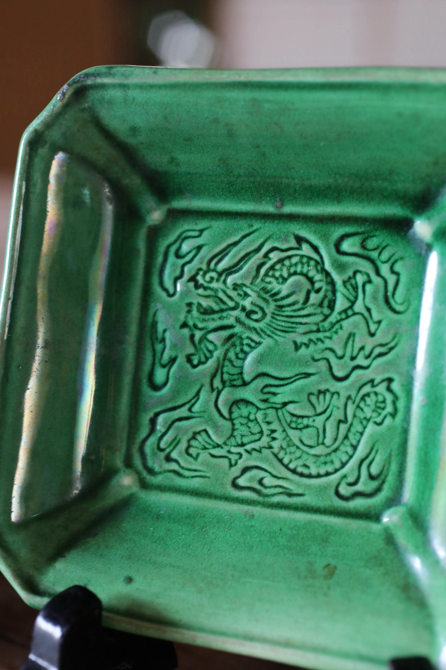 A green ceramic dish with an intricate dragon design on it.