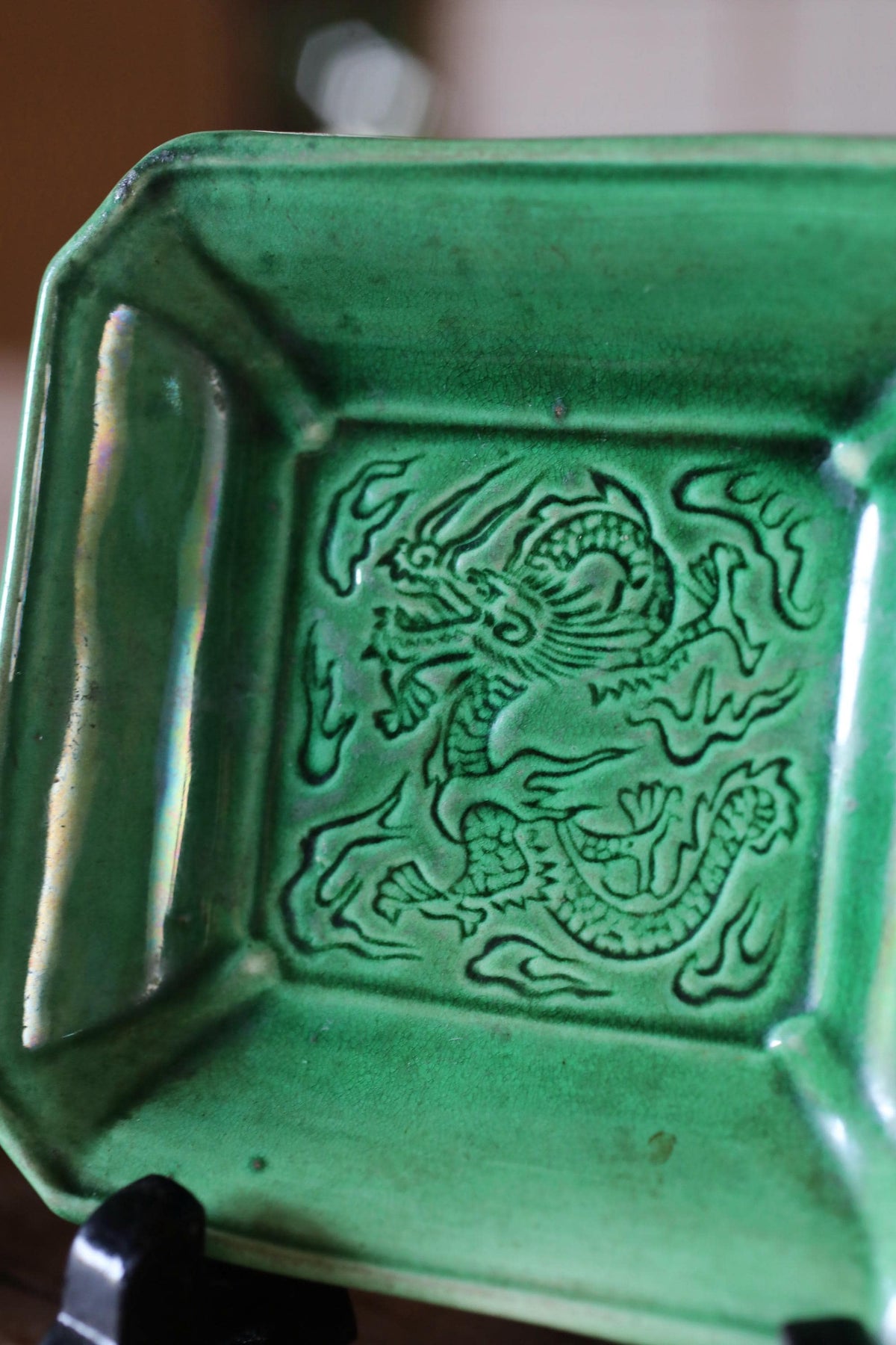 A green ceramic dish with an intricate dragon design on it.