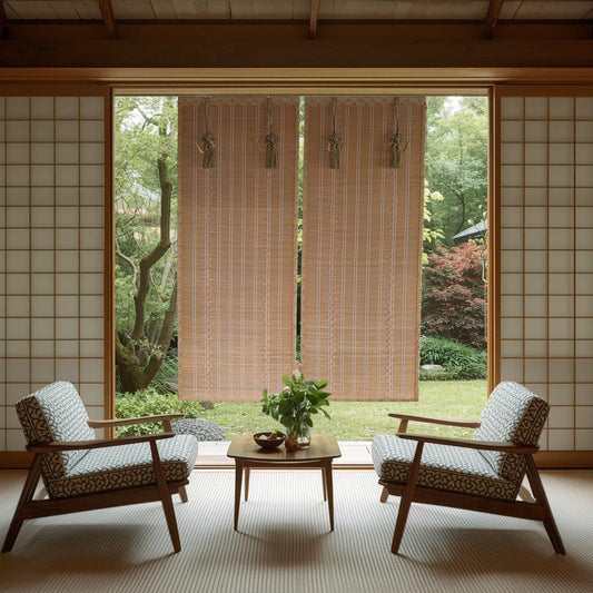 a serene and minimalist living space with a view of a lush garden through a large window. The room is furnished with two patterned armchairs and a wooden coffee table, creating a cozy seating area. The room is adorned with wooden blinds that allow natural light to filter in, and a small potted plant adds a touch of greenery to the space. The overall design and layout of the room create a harmonious and tranquil atmosphere.