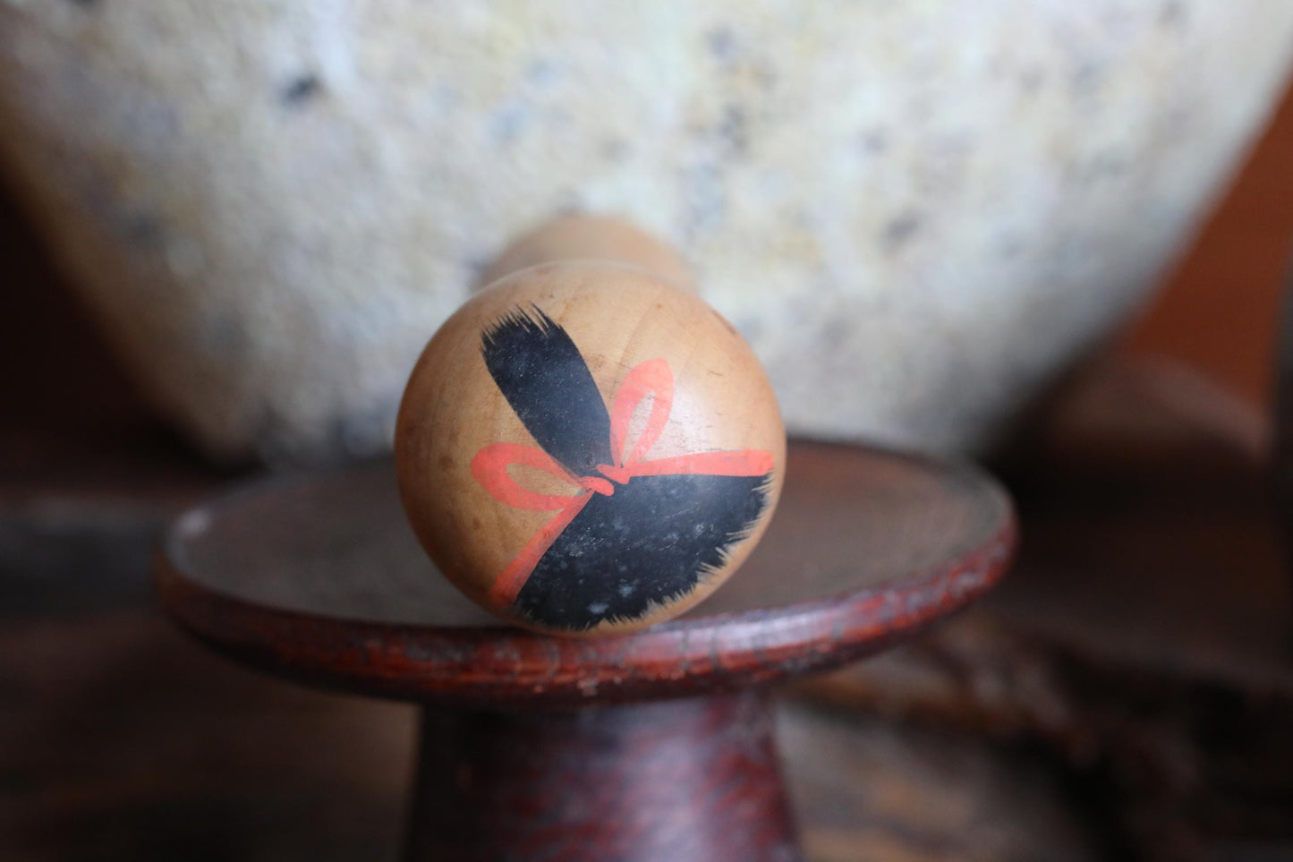 A wooden object with a bow design on it, placed on a wooden stand.