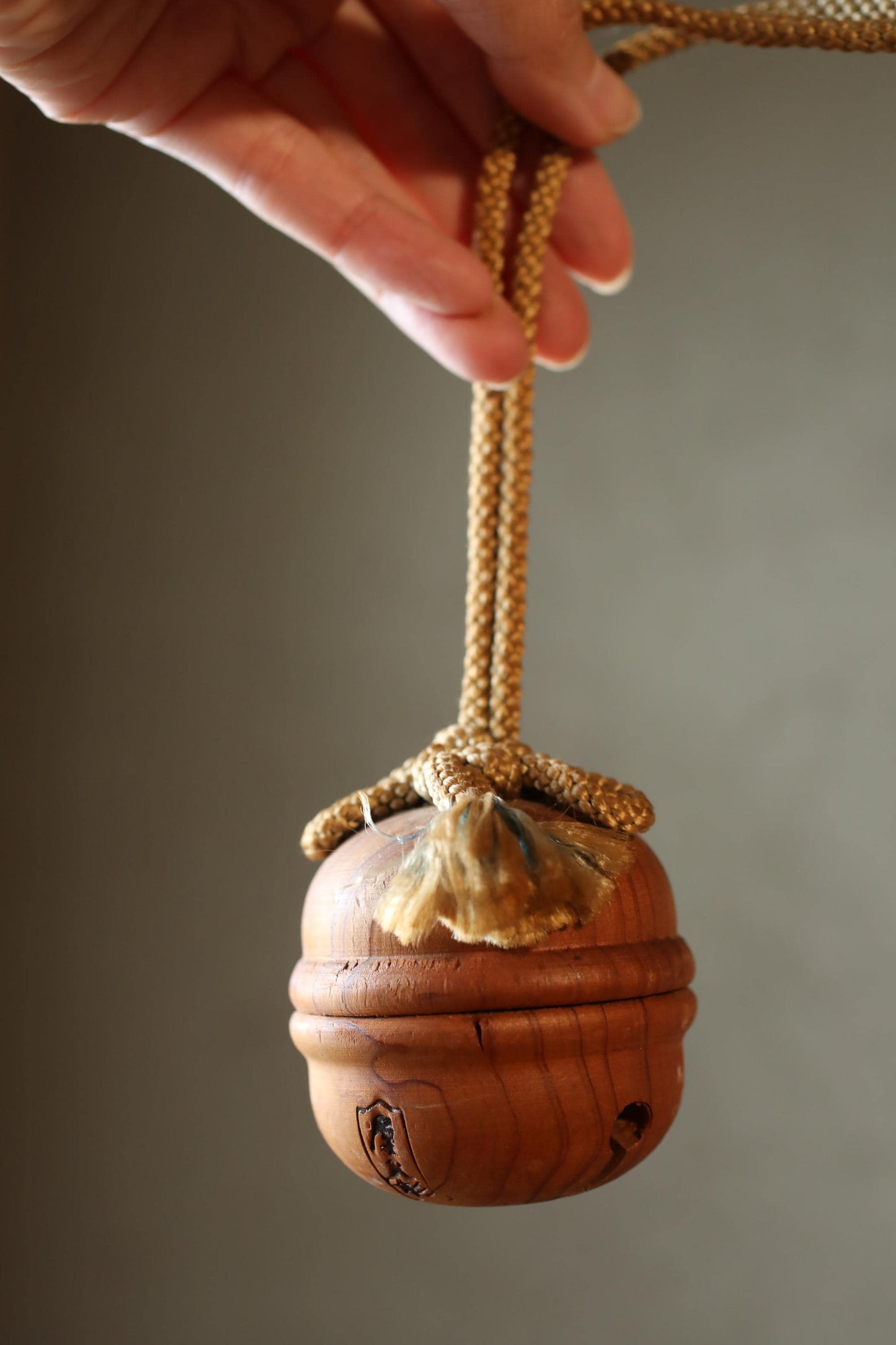 A hand is holding a wooden object with a rope attached to it.