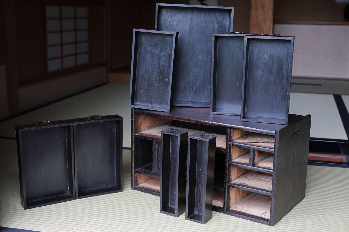 a collection of wooden boxes and trays, some of which are open, placed on a tatami mat.