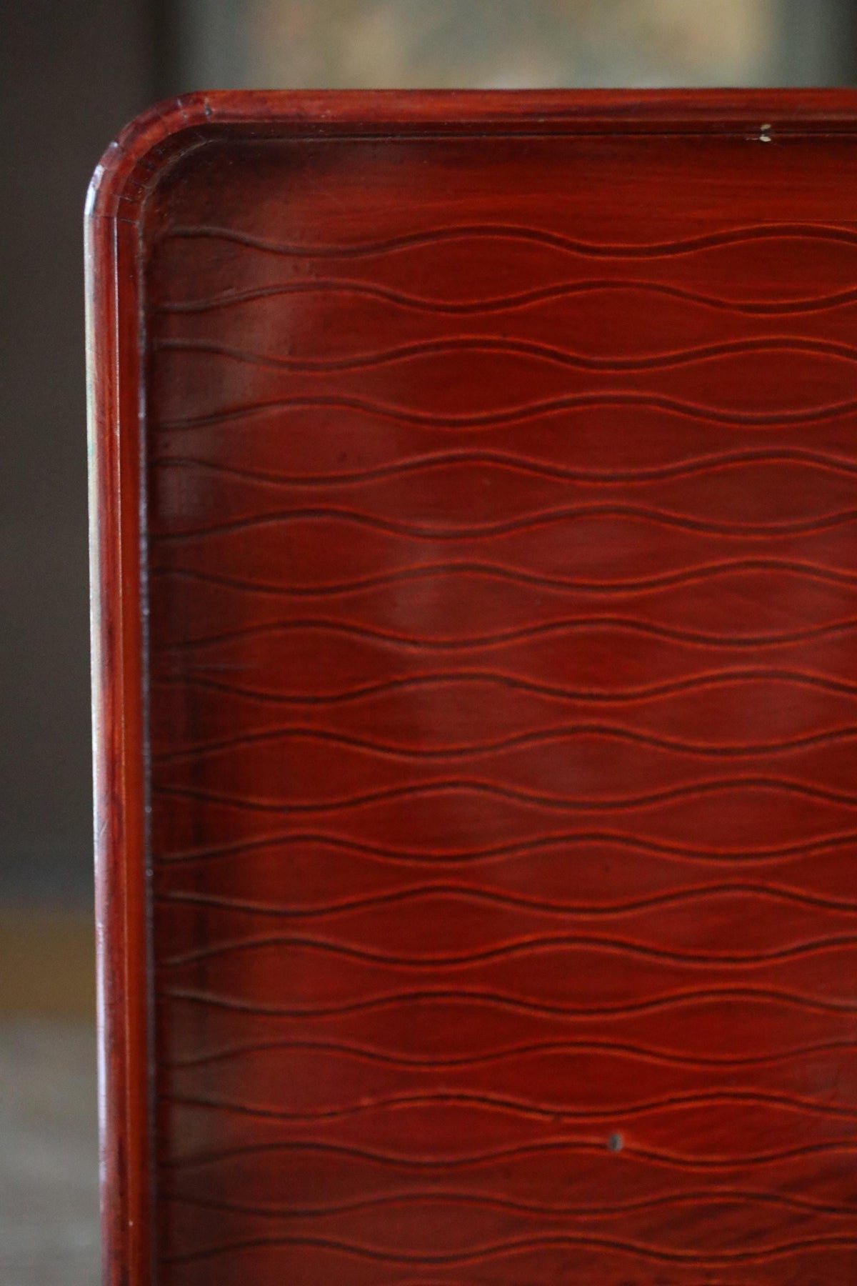 a close-up view of a wooden surface with a distinctive wavy pattern, likely made of a dark-colored wood.