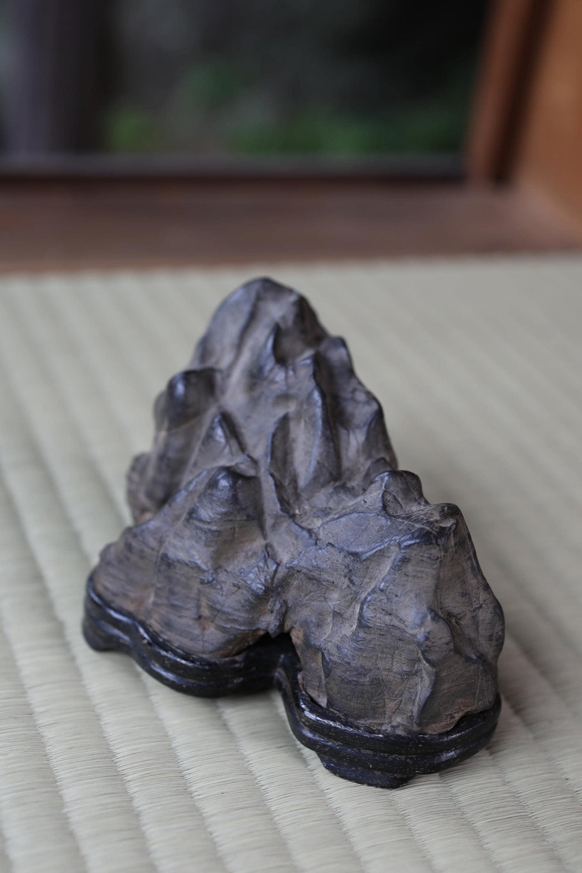 A close-up image of a dark gray rock formation on a woven mat.