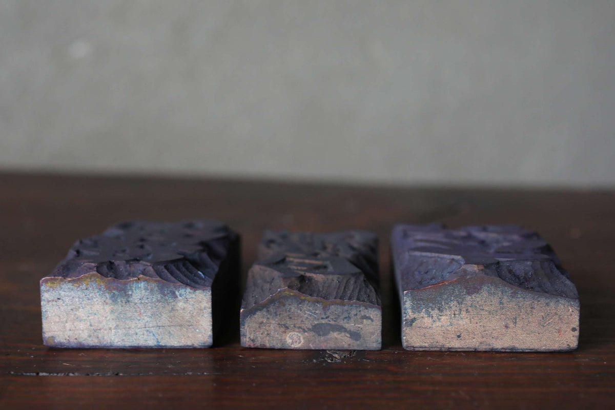 Three dark-colored rectangular blocks are arranged on a wooden surface.