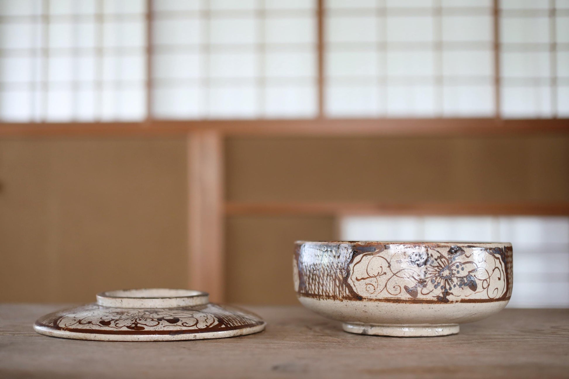 a bowl with a floral design on it, placed on a wooden surface.