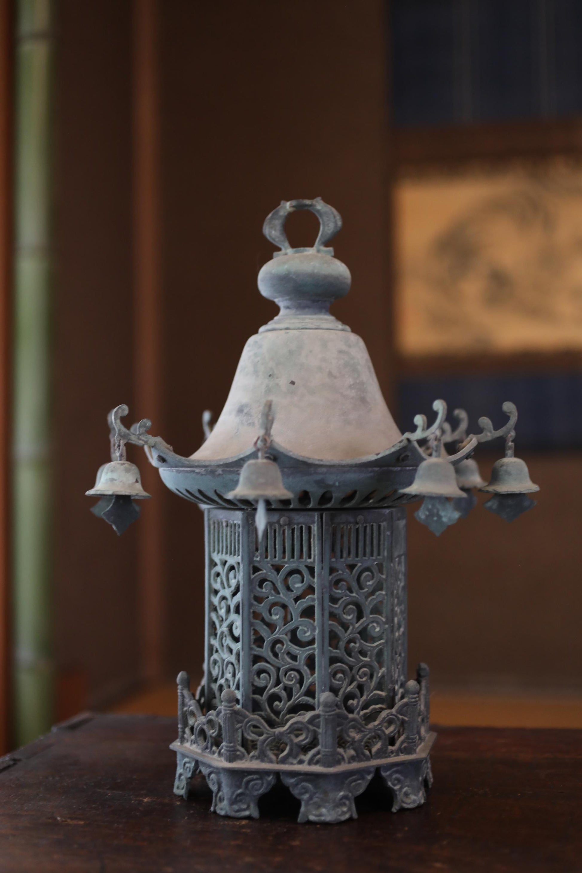 An ornate, antique-looking metal lantern or lamp with intricate designs and decorations, sitting on a wooden surface.