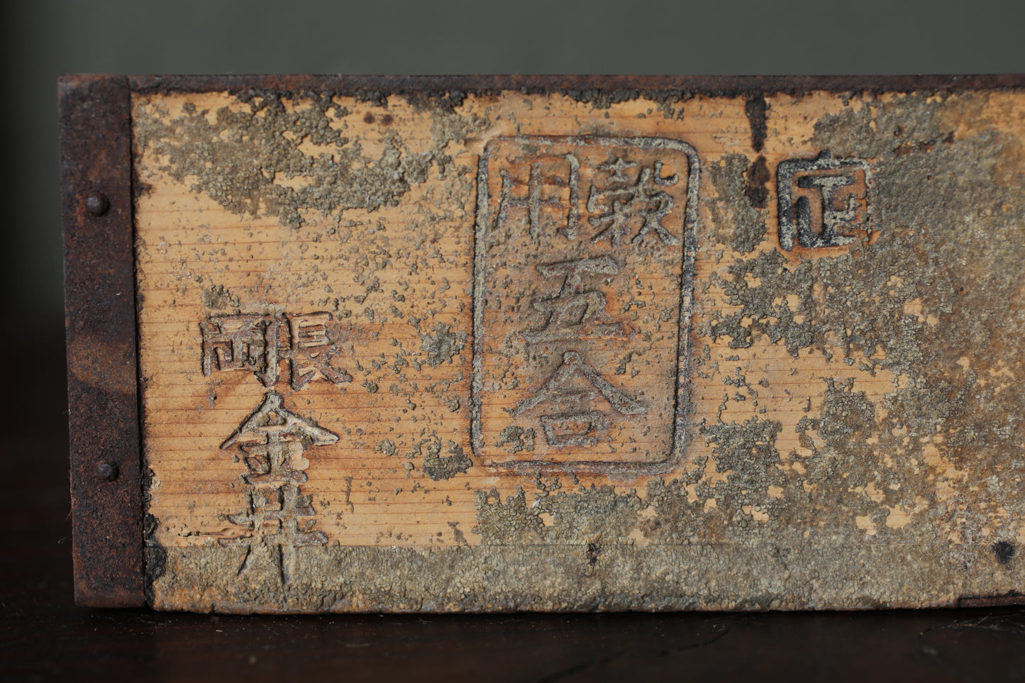 a weathered wooden surface with various markings and symbols, including some Japanese characters.