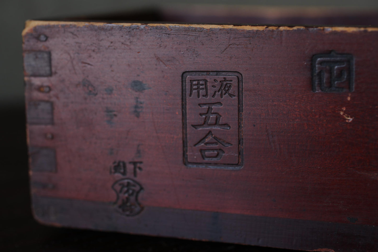 a close-up view of a wooden surface with a dark brown color and some text or symbols in a foreign language.