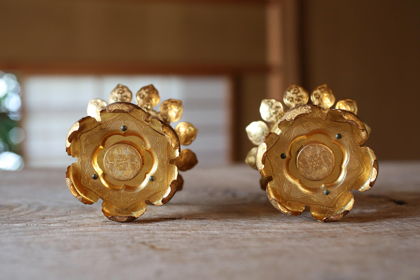 two ornate golden objects with intricate designs, placed on a wooden surface.