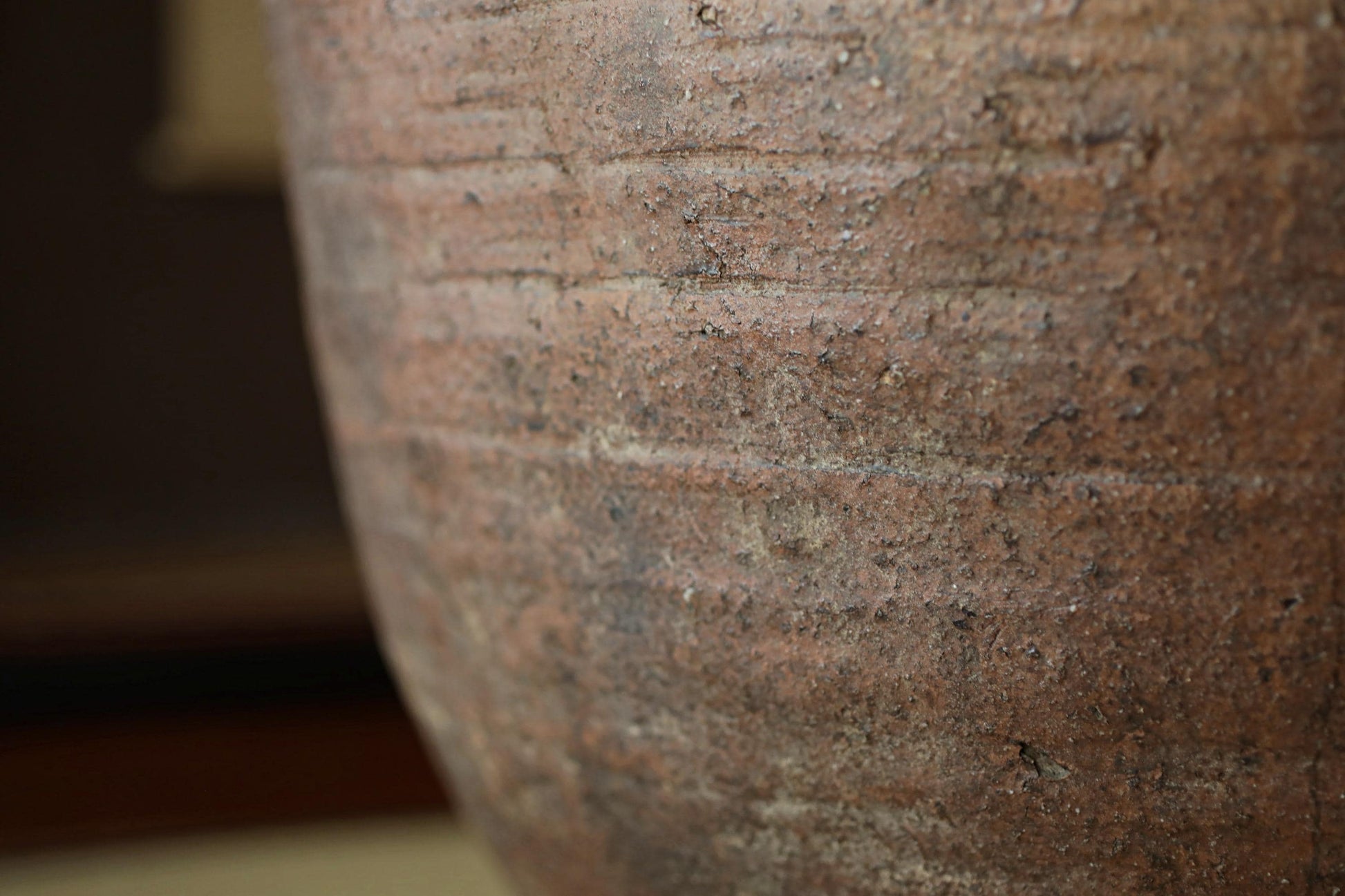 A close-up view of a weathered, textured surface, possibly a piece of pottery or a wall, with visible cracks and stains.