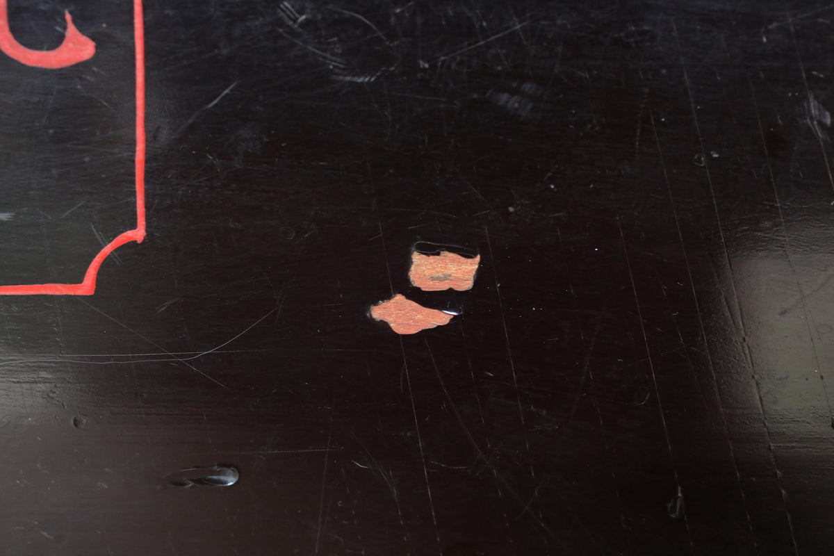 a close-up view of a black surface with a red line running across it. There is a small, orange-colored object or shape on the surface, which appears to be a tear or a hole.