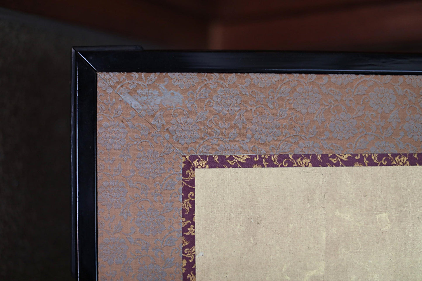 a close-up view of a framed artwork with a decorative border and a floral pattern on the border.