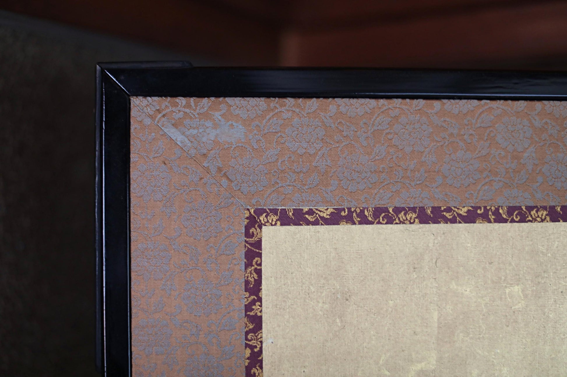a close-up view of a framed artwork with a decorative border and a floral pattern on the border.