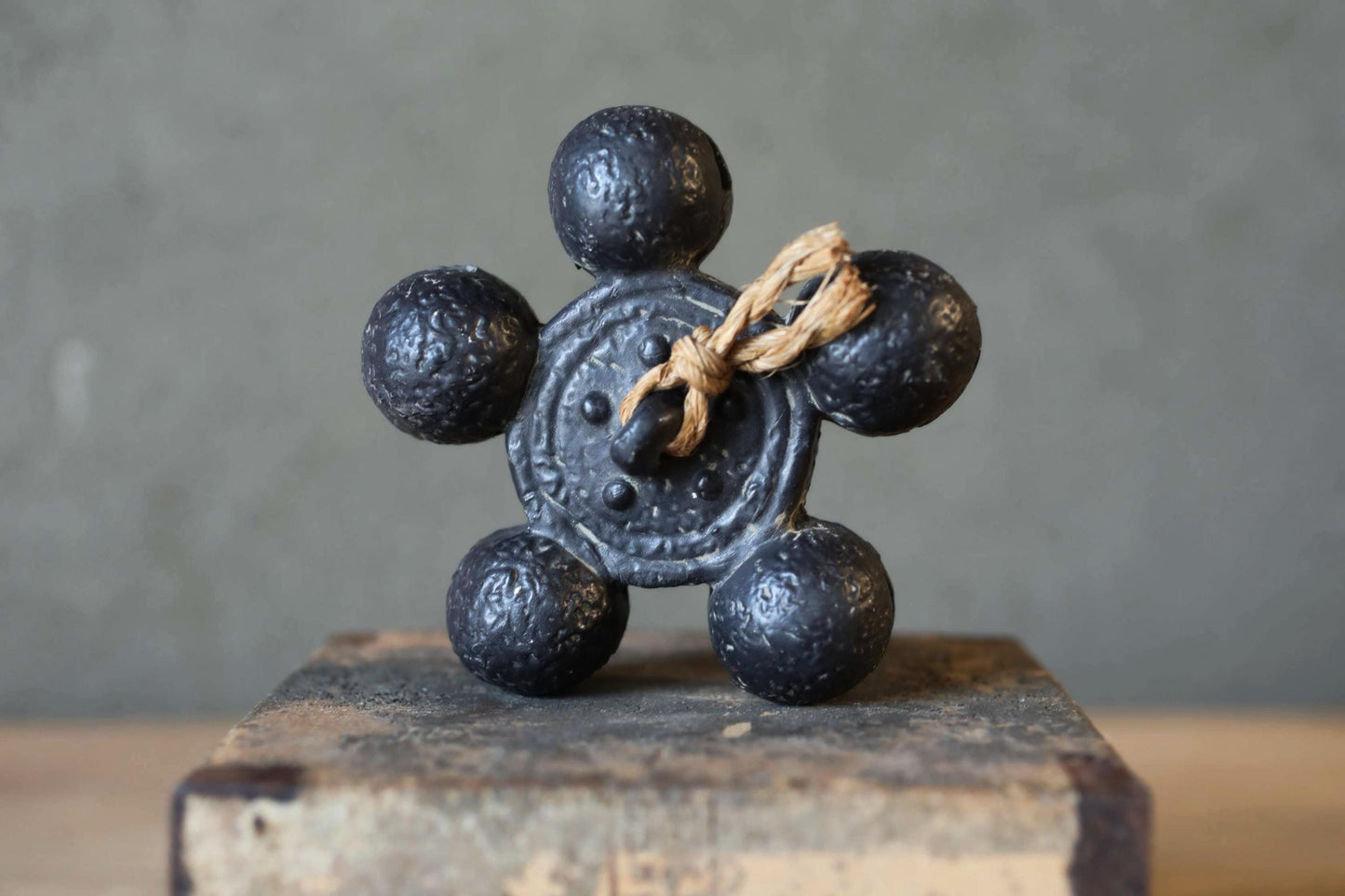 A black metal object with six round balls attached to it, sitting on a wooden surface.