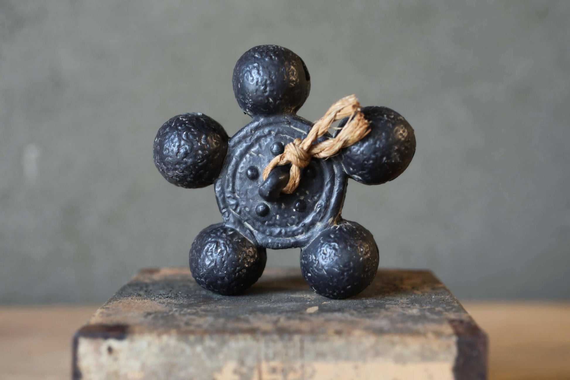 A black metal object with six round balls attached to it, sitting on a wooden surface.