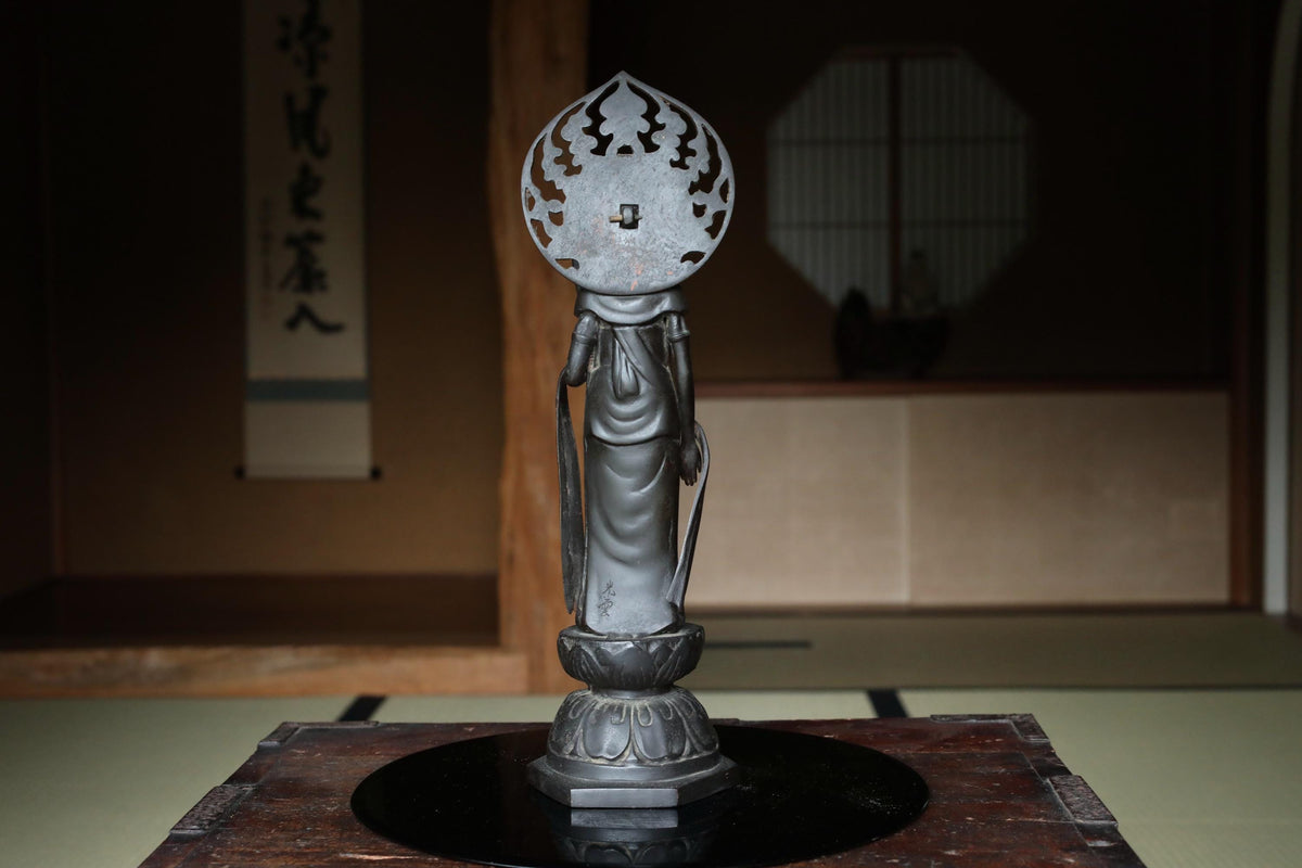 a statue of a deity, possibly a Buddhist figure, placed on a wooden surface.