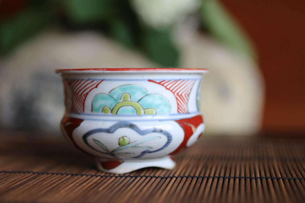 A colorful ceramic bowl with a floral design sits on a bamboo mat.