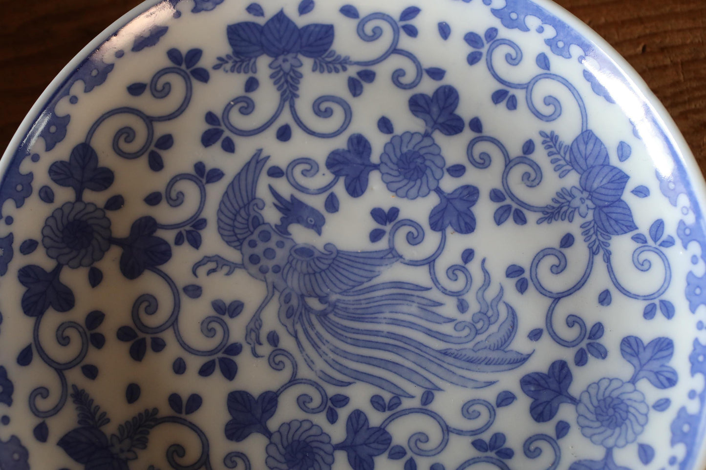 a blue and white plate with a decorative design of a bird and flowers.