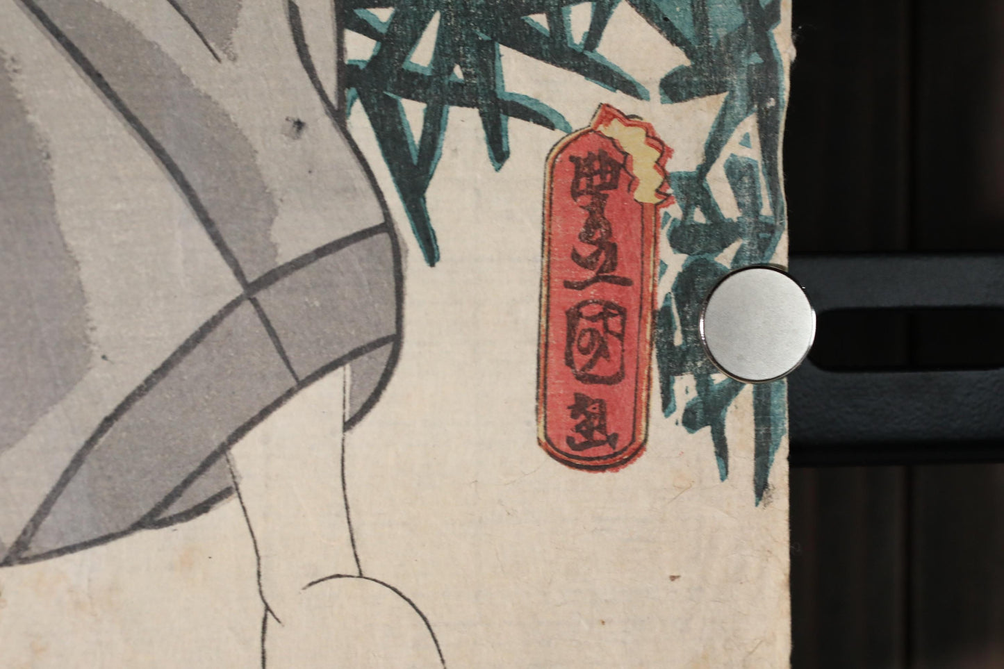 a close-up view of a red and white sign with Japanese characters on it, placed on a surface with a blurred background.