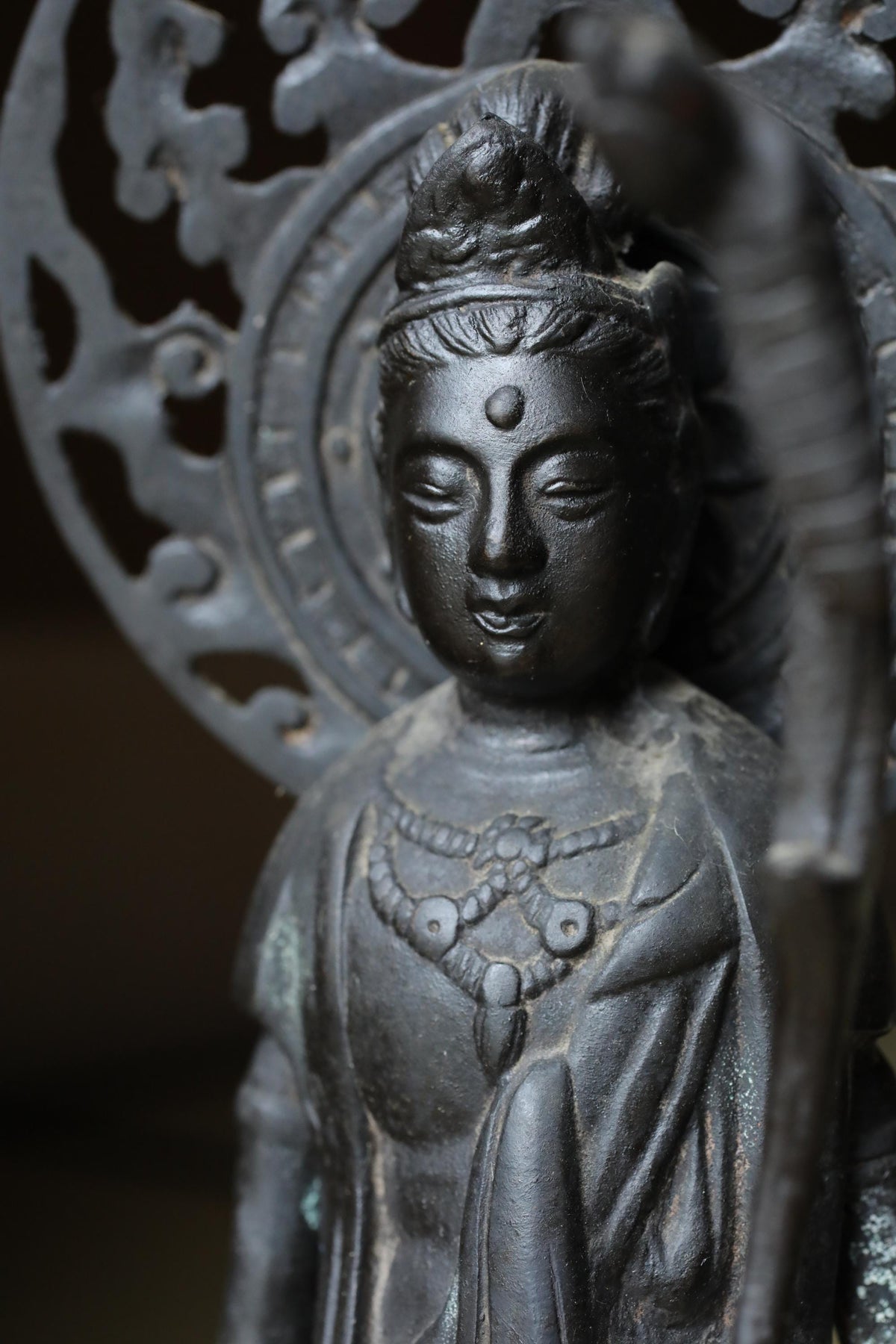 A close-up image of a black metal statue depicting a deity or religious figure.