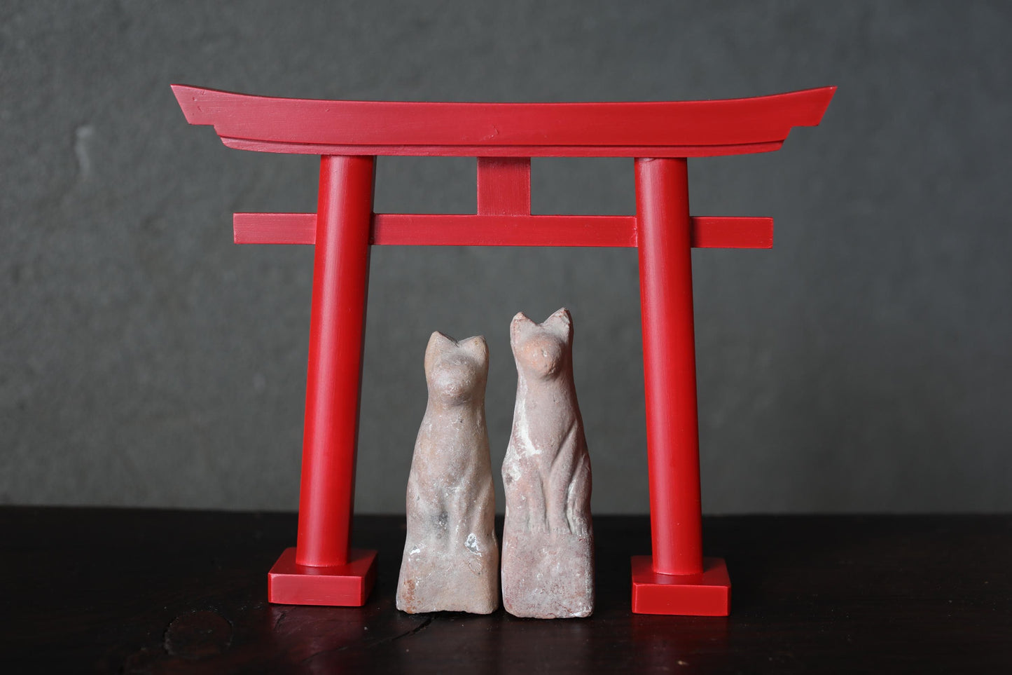 two small statues of cats standing in front of a red torii gate.