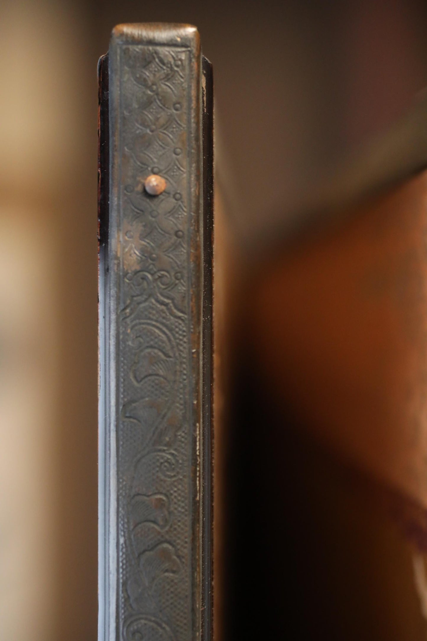 a close-up view of a decorative metal object, possibly a handle or a decorative element, with a blurred background.