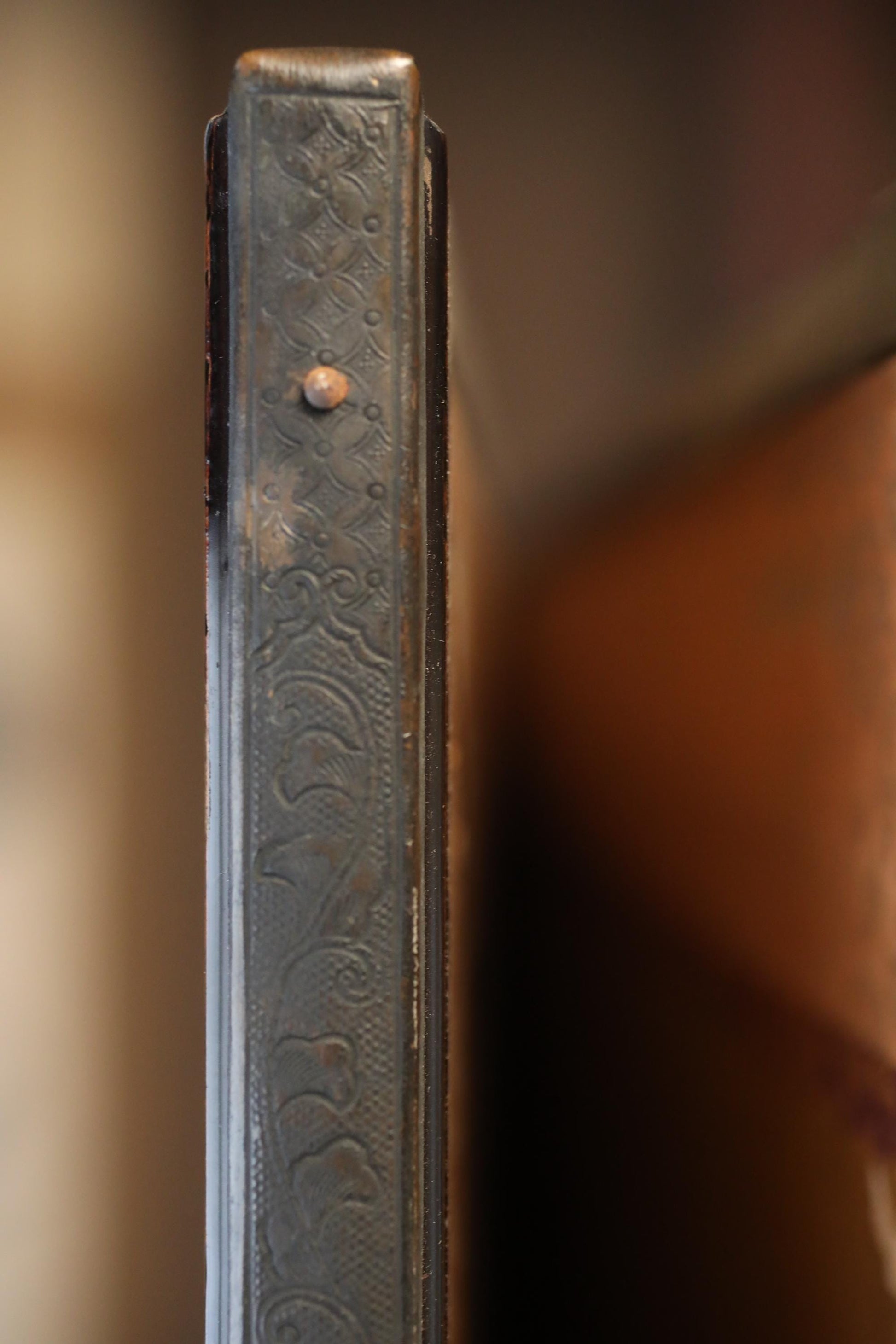 a close-up view of a decorative metal object, possibly a handle or a decorative element, with a blurred background.