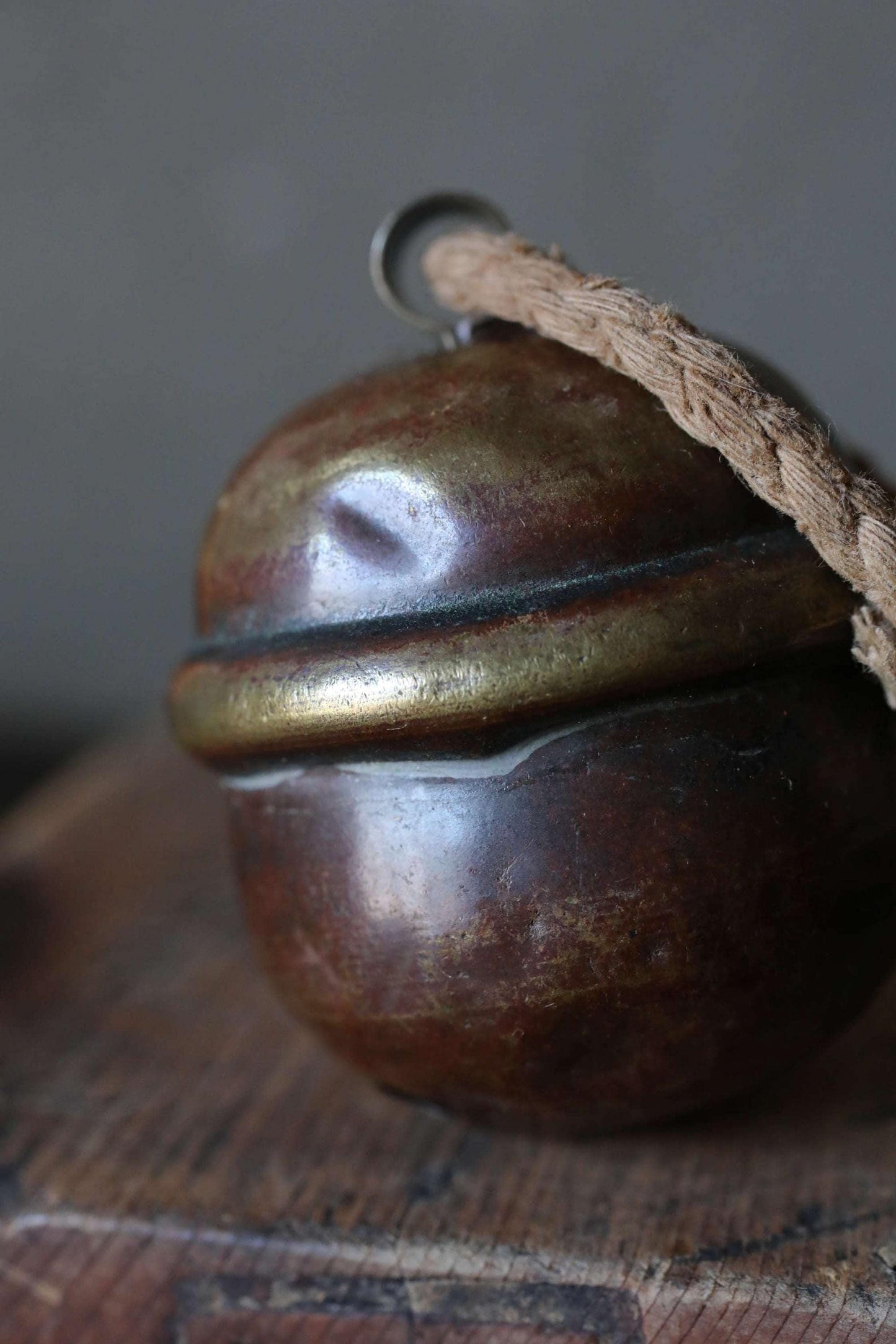 A close-up image of a round, metallic object with a rope hanging from it, resting on a wooden surface.