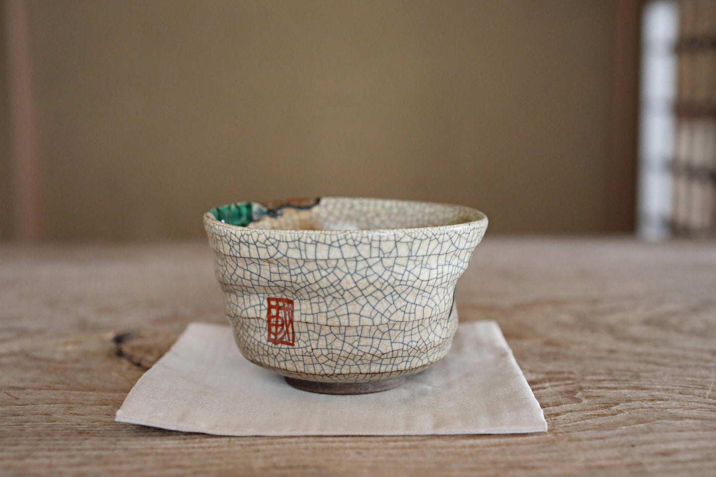 A ceramic bowl with a cracked and textured design sits on a white napkin on a wooden table.
