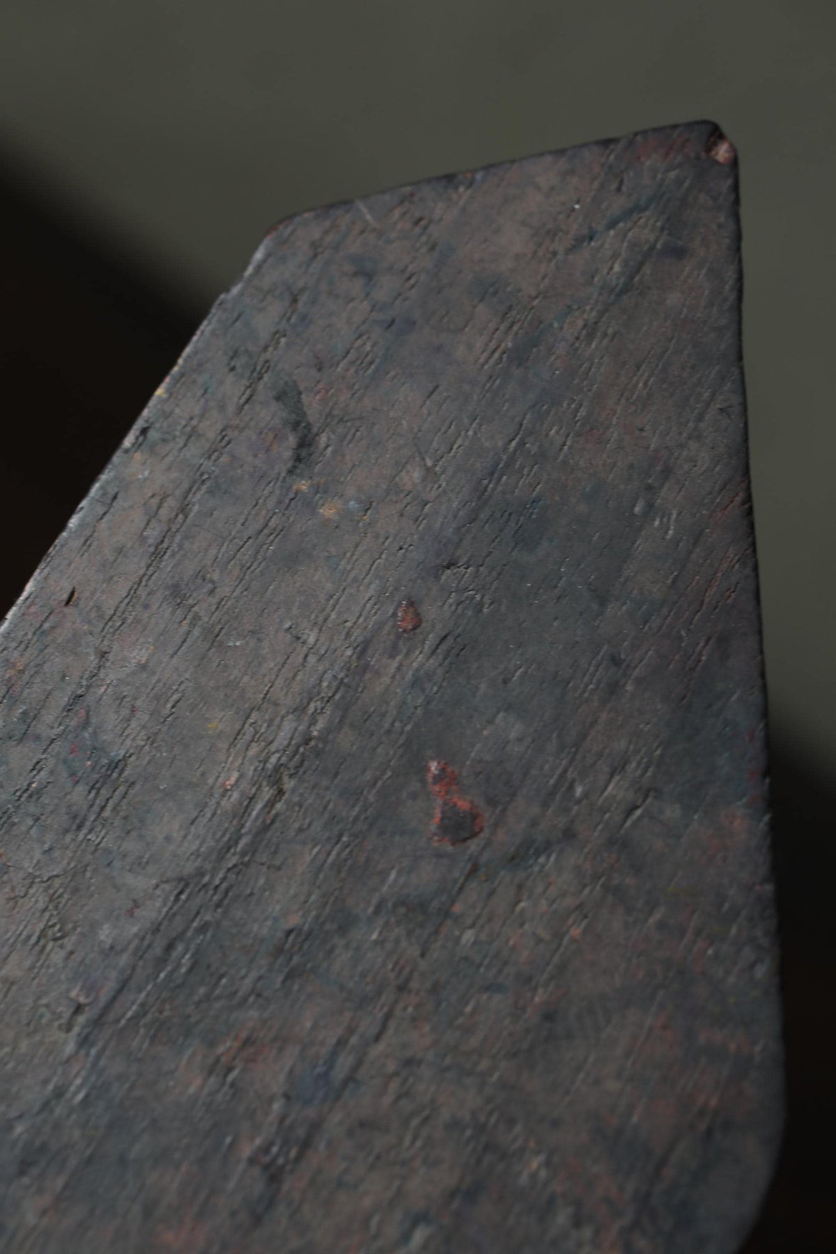 a close-up view of a dark, textured surface, possibly a piece of metal or a wooden object.
