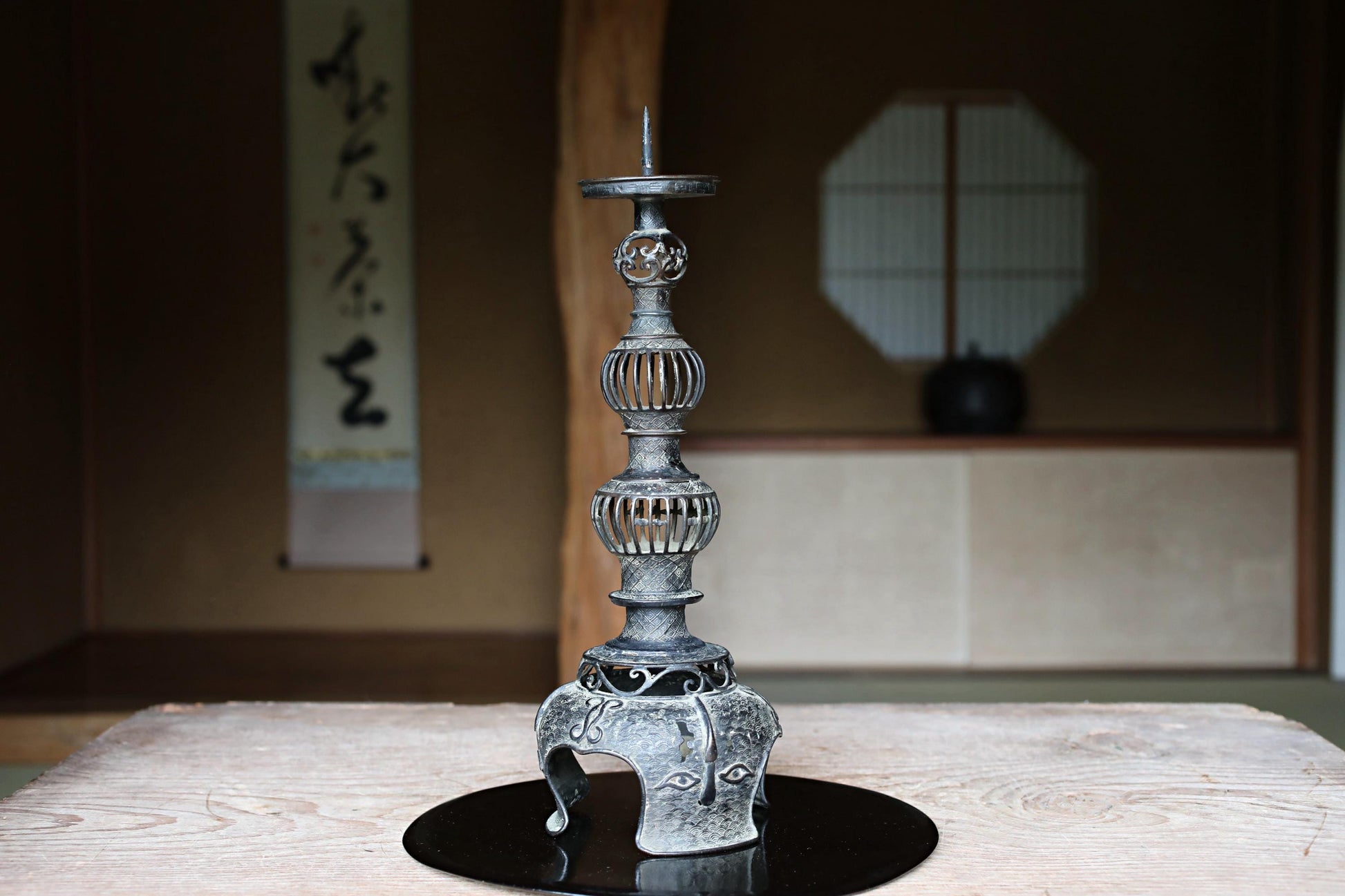 a decorative metal candlestick with a tall, ornate design on a wooden surface.