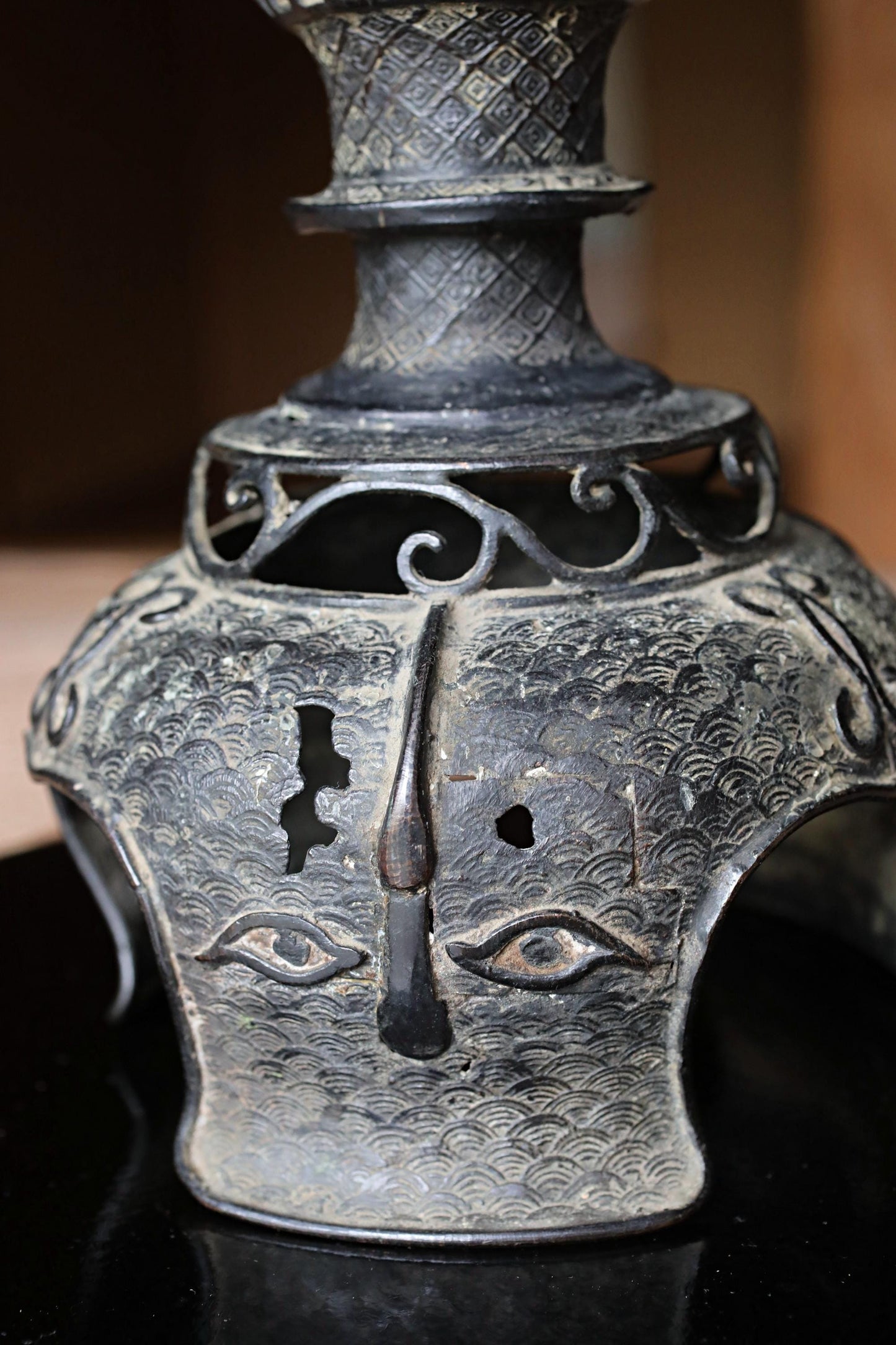 a close-up view of an ornate, antique-looking metal object with a face-like design on its surface.