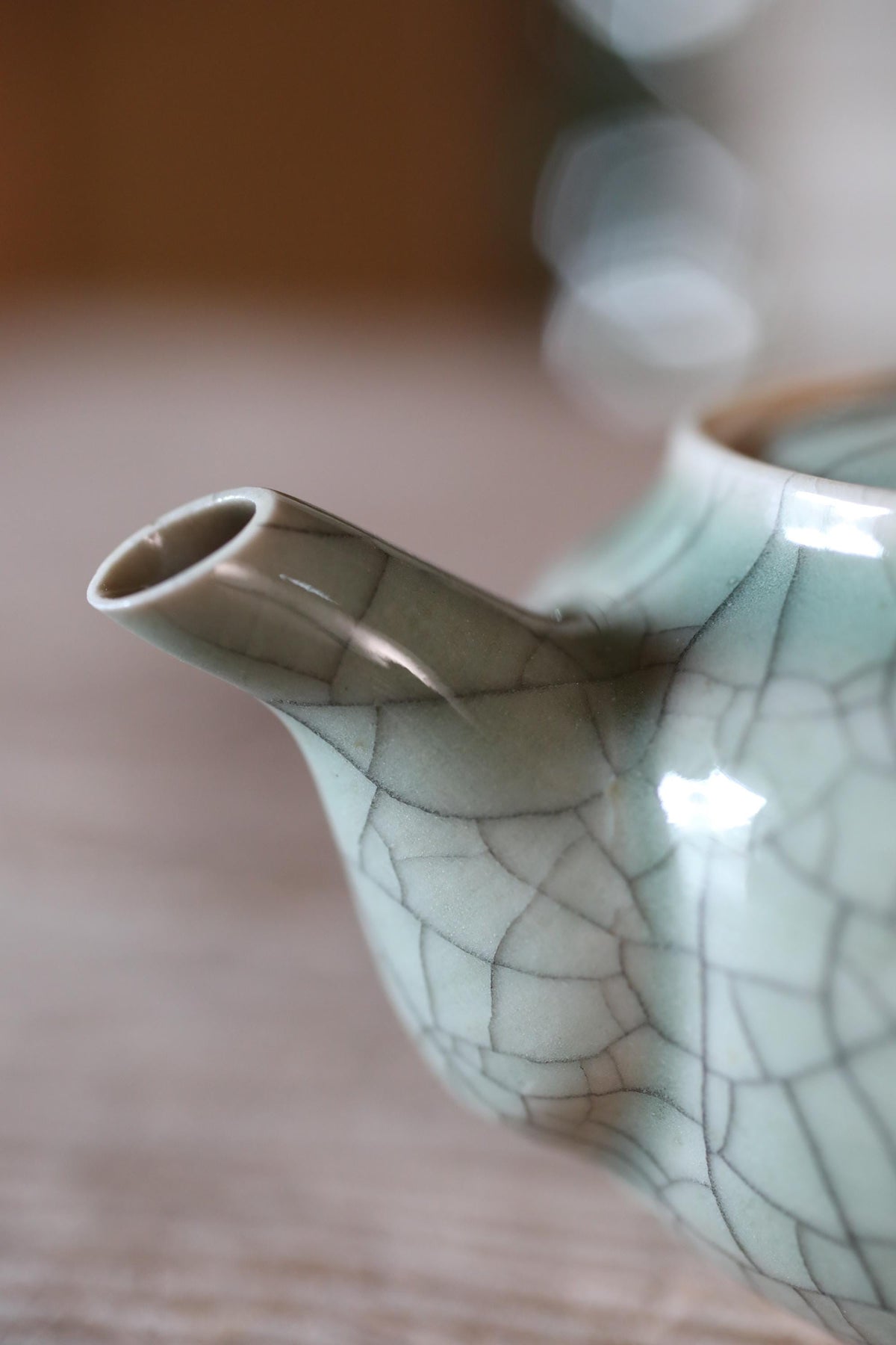 A close-up view of a ceramic teapot with a textured, cracked pattern in shades of green and white.