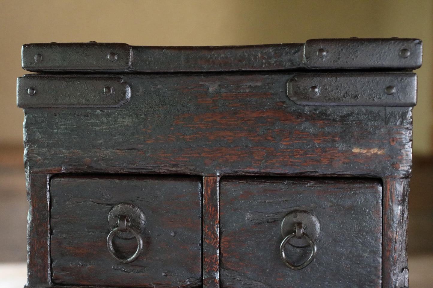 a close-up view of a dark wooden chest with two drawers and metal hardware.