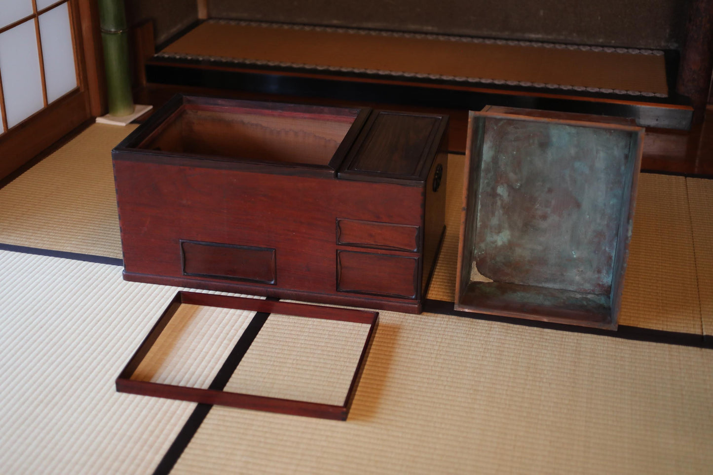 a wooden box with a metal lid, placed on a tatami mat.