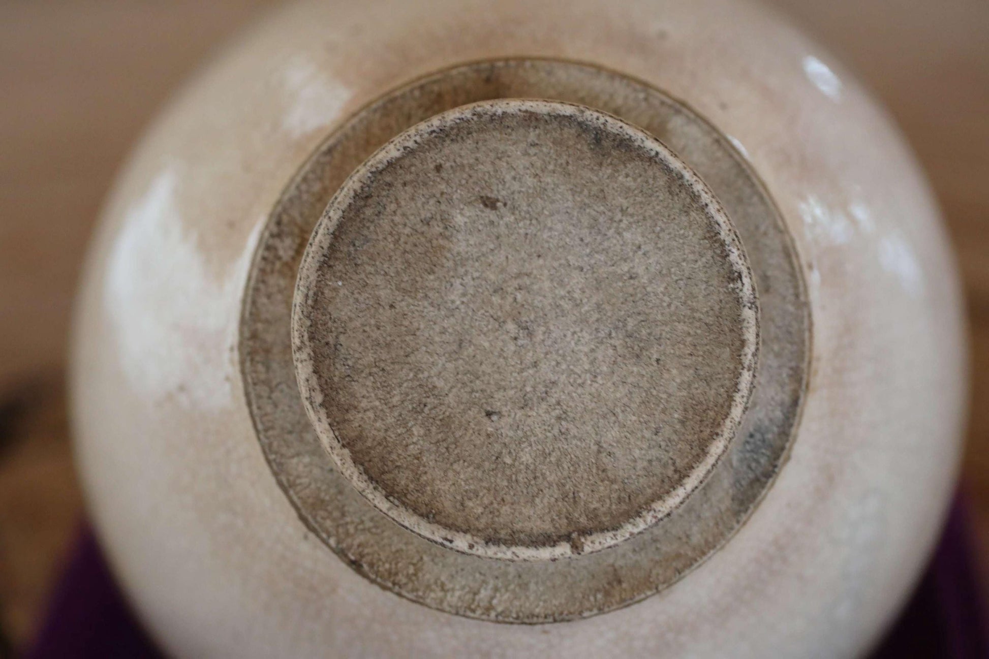 A close-up view of the bottom of a white ceramic bowl or vase, with a textured surface and a circular opening at the top.