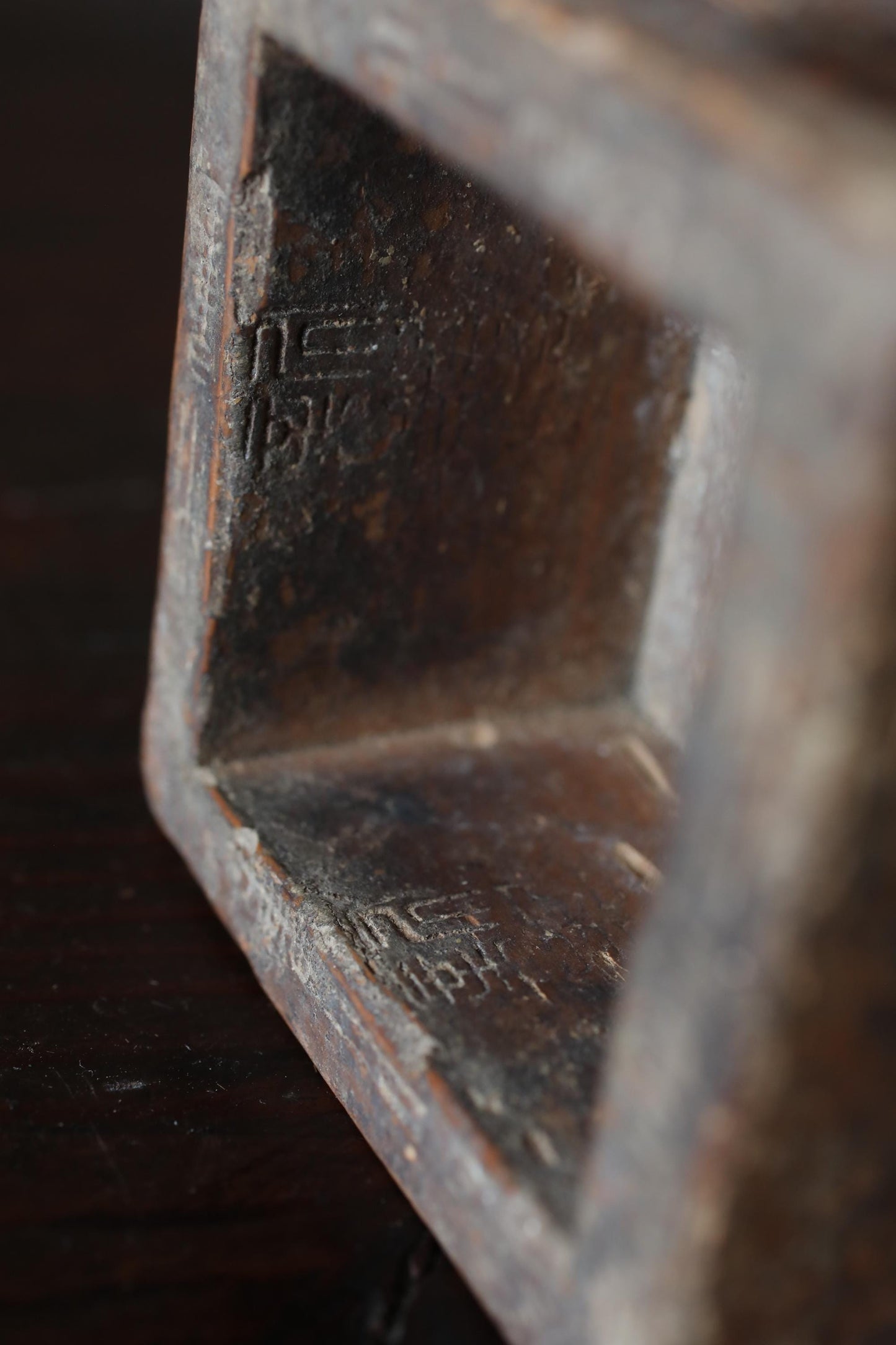 a close-up view of a metal object, possibly a sculpture or a piece of furniture, with a textured surface and some markings or engravings visible.