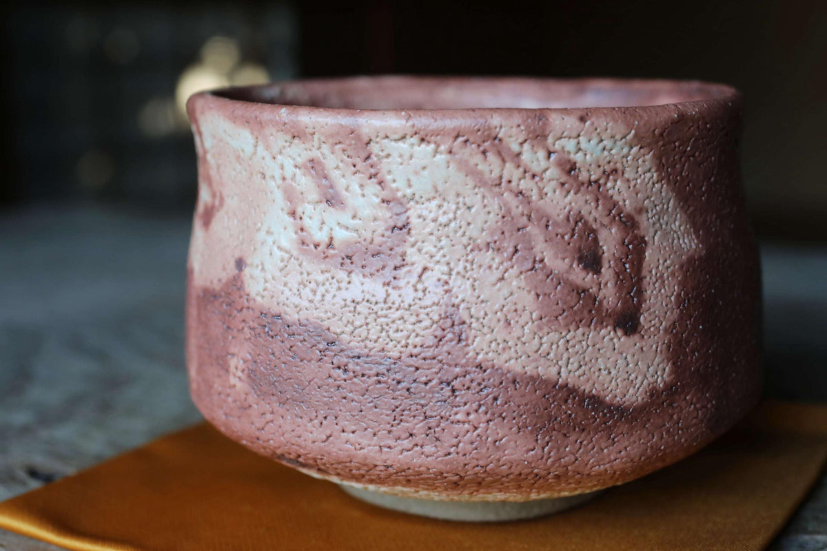A close-up image of a ceramic bowl with a textured surface, resting on a wooden surface.