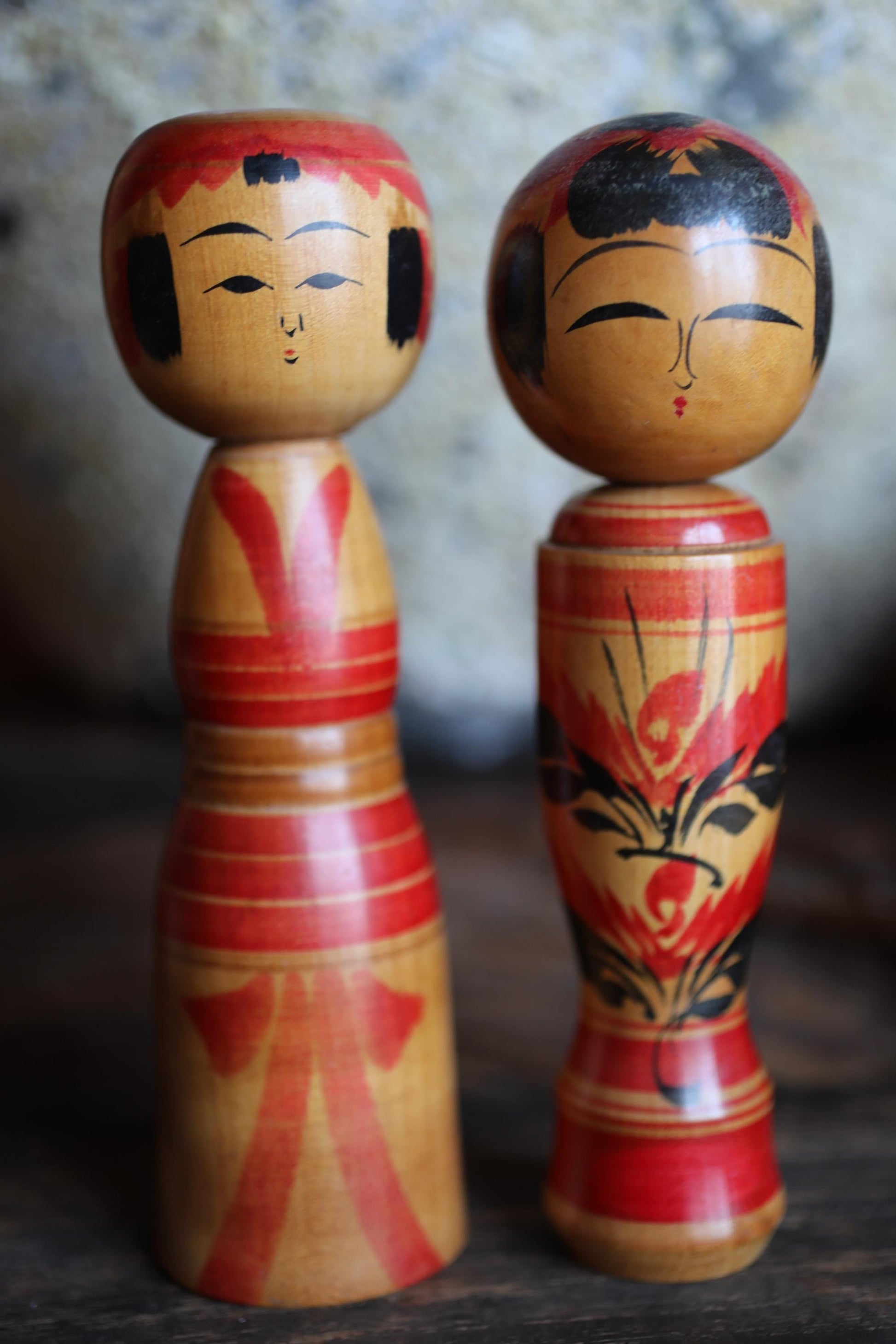 Two wooden dolls with red and gold designs stand next to each other.