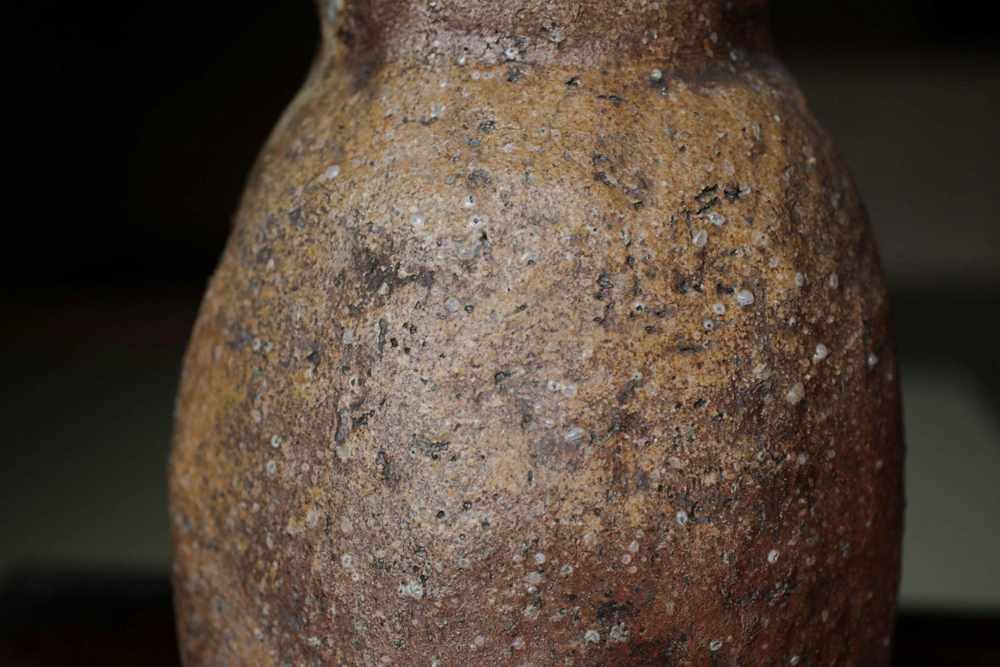 A close-up image of a weathered, brown vase with a speckled texture.
