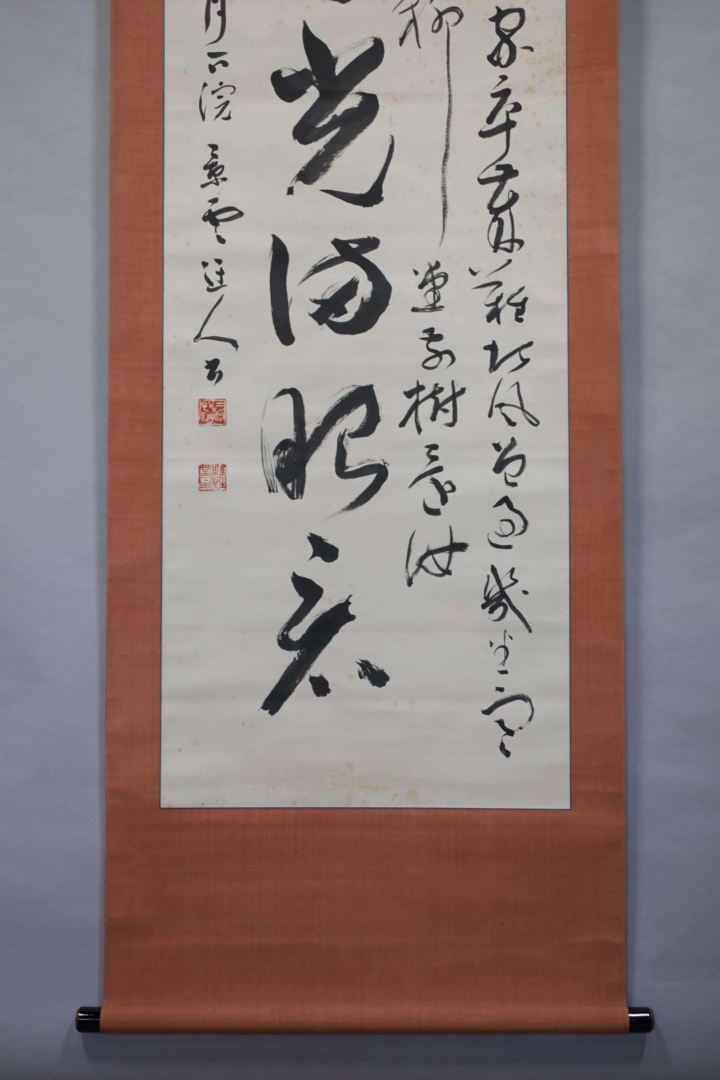 a large scroll with Chinese characters on it. The scroll is hanging on a wall, and the text appears to be in a foreign language. The scroll is quite large, occupying a significant portion of the wall space. The image does not contain any other objects or text, and the focus is solely on the scroll and its characters.
